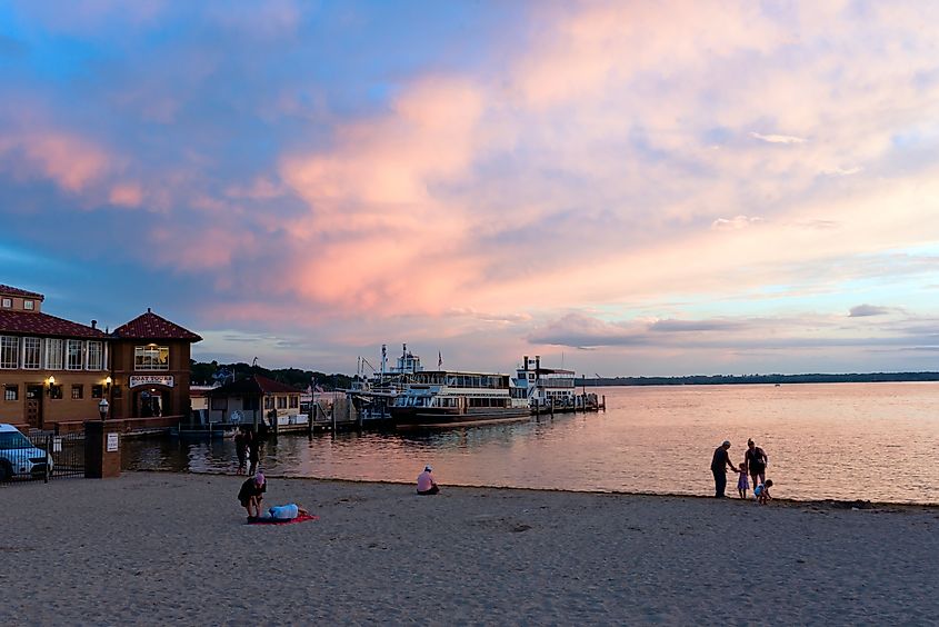 People gathering at the beach near Lake Geneva, showing the boat docks during a gorgeous pinky and cloudy sunset. Editorial credit: BetoVM / Shutterstock.com