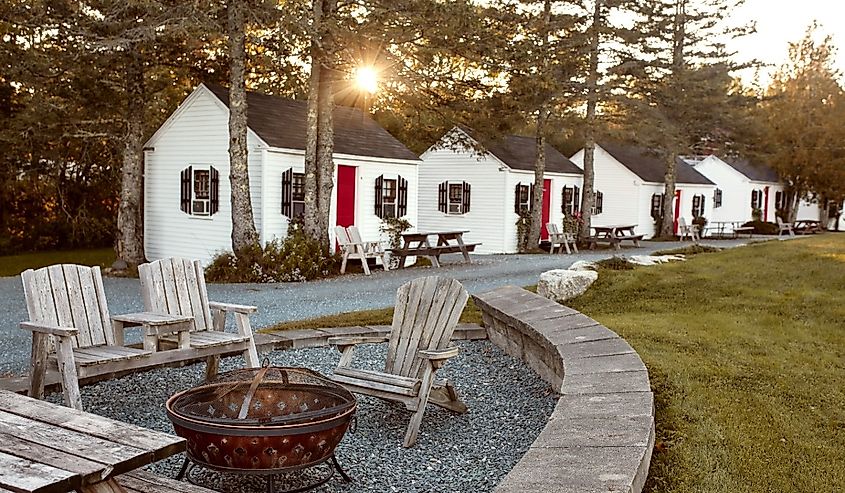 Cottages at Open Hearth Inn Hotel surrounded by lush foliage at sunset in Trenton, Maine.