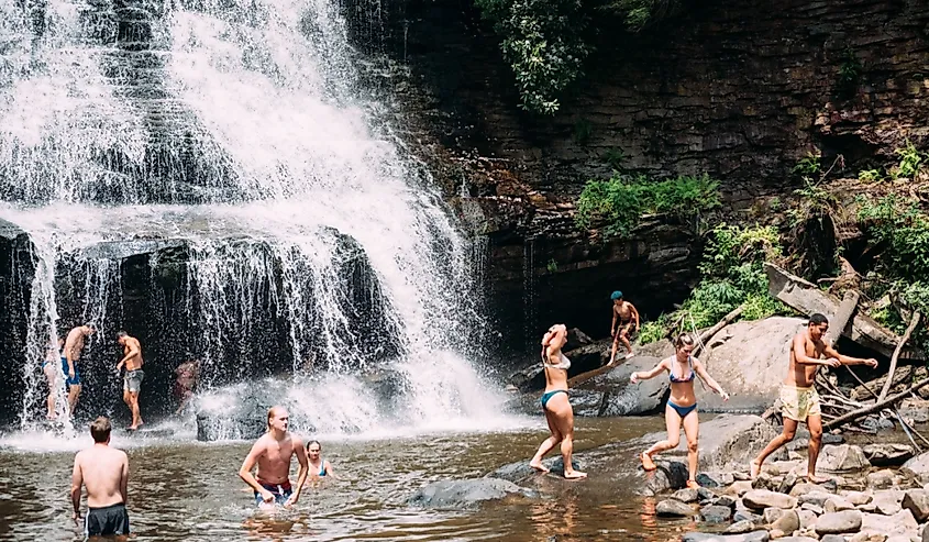 Tourists and visitors swimming under the waterfall at Swallow Falls State Park