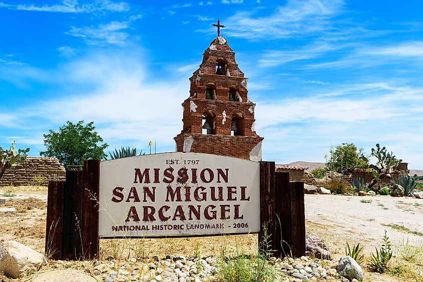 Mission San Miguel Arcangel sign and historic Bell Tower under beautiful blue sky. - San Miguel, California