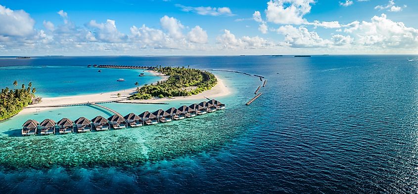 Resort villas lined along the coast of an island in the Maldives.