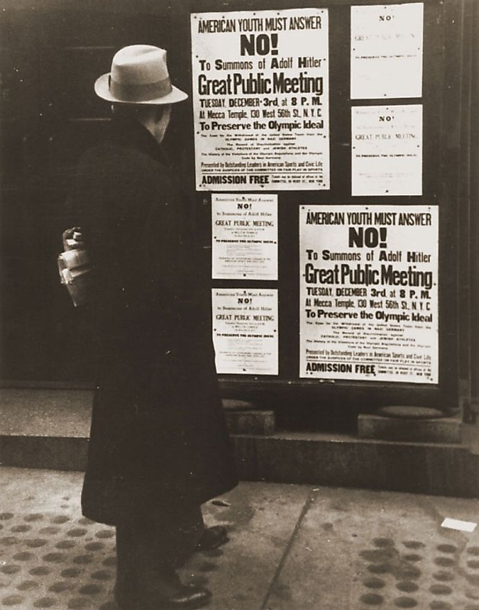 Pedestrian reading poster announcing public meeting to boycott 1936 Olympics. 