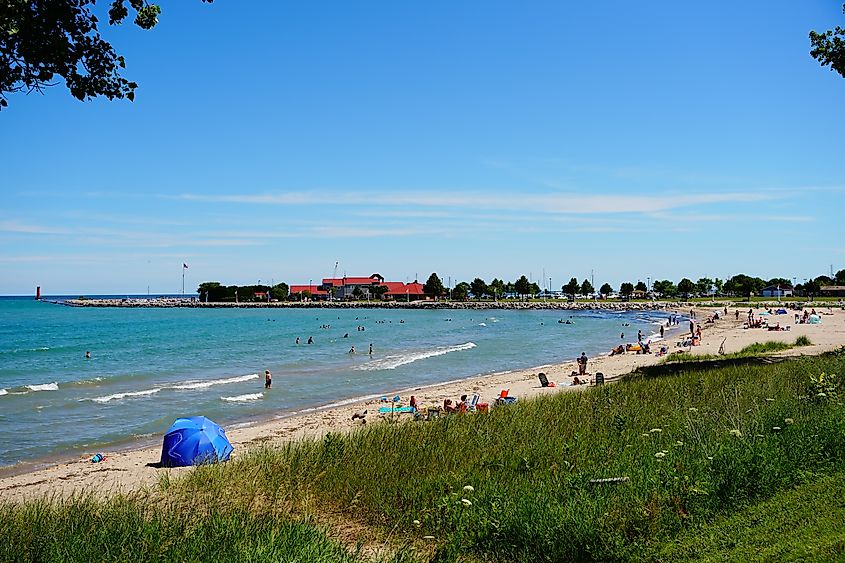 Families enjoying a sunny day on the sandy beach along Lake Michigan's shoreline in Sheboygan, Wisconsin.