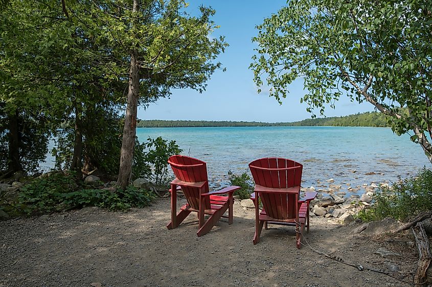 Two bright red wooden chairs on the Georgian Bay shore