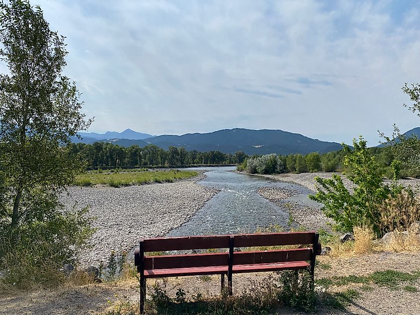 A wooden bench overlooking the Yellowstone River and the backdrop mountain ranges.