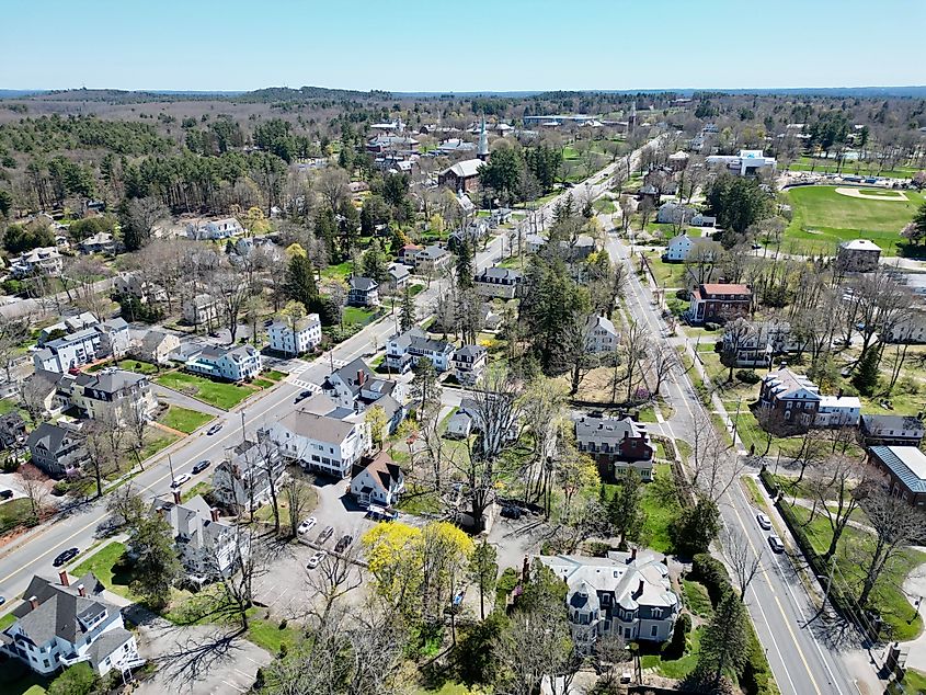 Aerial view of Andover, Massachusetts, showcasing the town's buildings, streets, and green spaces from above, with a mix of historic and modern structures surrounded by tree-lined neighborhoods.