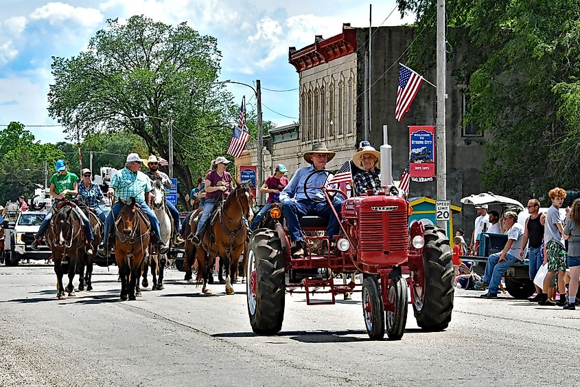 Elderly local farmer drives 1939 Farmall Model H tractor leading Cowboys and Cowgirls in Flint Hills Rodeo parade, Strong City, Kansas, USA.