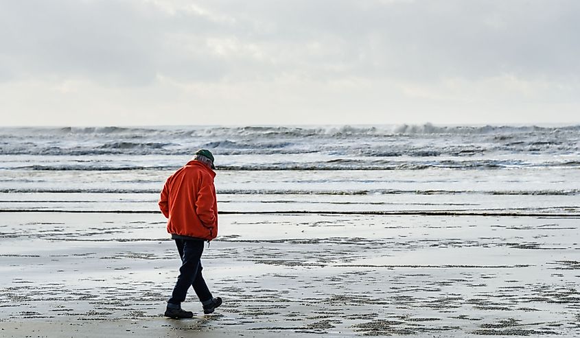 Senior man walking on the beach at low tide on a stormy day at Copalis Beach, Ocean Shores, Washington State