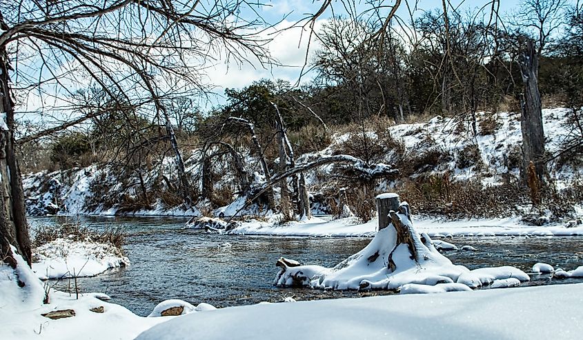 Tree stump in the Blanco River covered in snow, Wimberley, Texas.