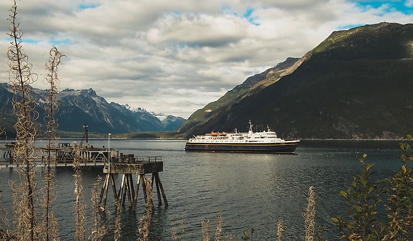Ferry boat is slowly sailing to harbour in Inside Passage Alaska carrying tourists and passengers going from or to holiday and vacation in autumn close to Haines