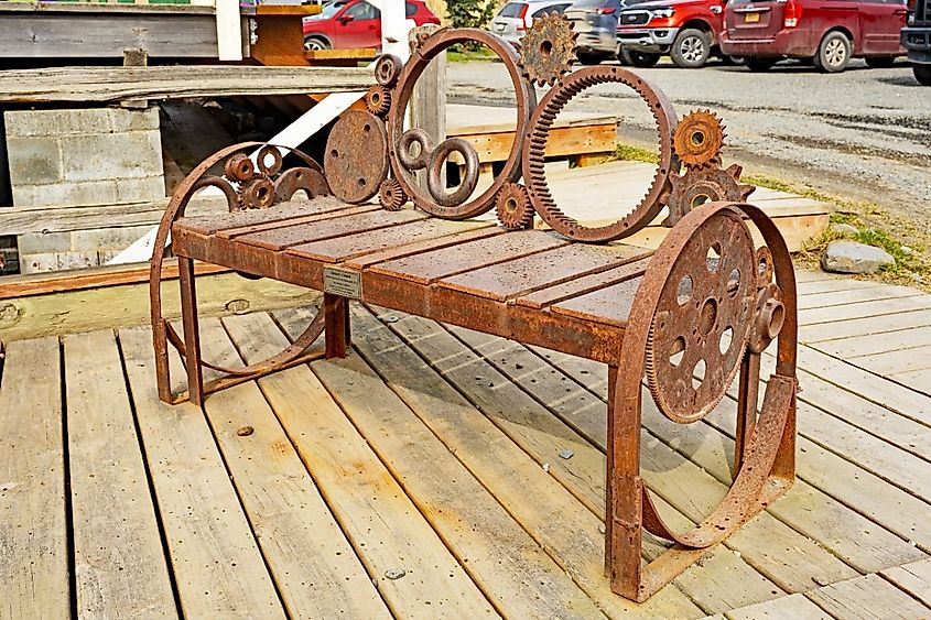 A public bench is fashioned out of wheel and cogs and is situated outside the Bunnell Street Arts Center in Homer.