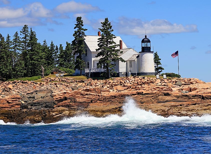 Winter Harbor Lighthouse with dramatic waves of Atlantic Ocean on the foreground, Maine, USA