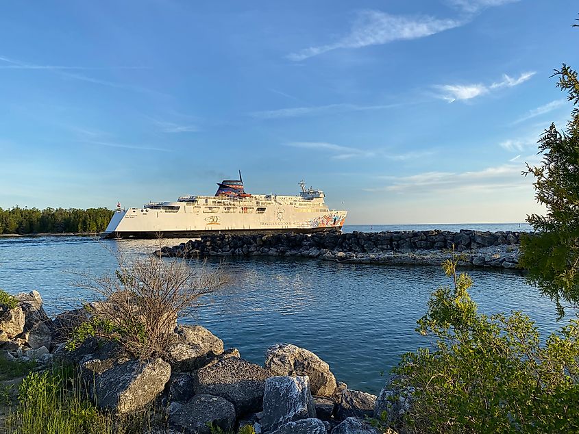 A large white ferry with Indigenous art painted on it pulls out of an island port