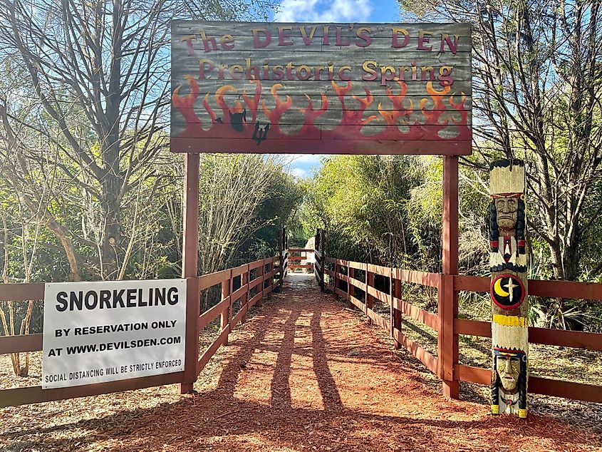 A welcome sign with devil and pitchfork stands over the entrance to the sinkhole and dive resort at Devil's Den in Williston, Florida.