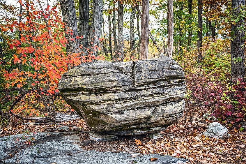 A large glacial boulder on the trail in the Autumn woods of Jenny Jump State Forest in New Jersey.