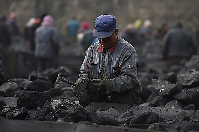 In this photo taken on November 20, 2015, a worker sorts coal on a conveyer belt, near a coal mine at Datong, in China's northern Shanxi province. [Photo/VCG]