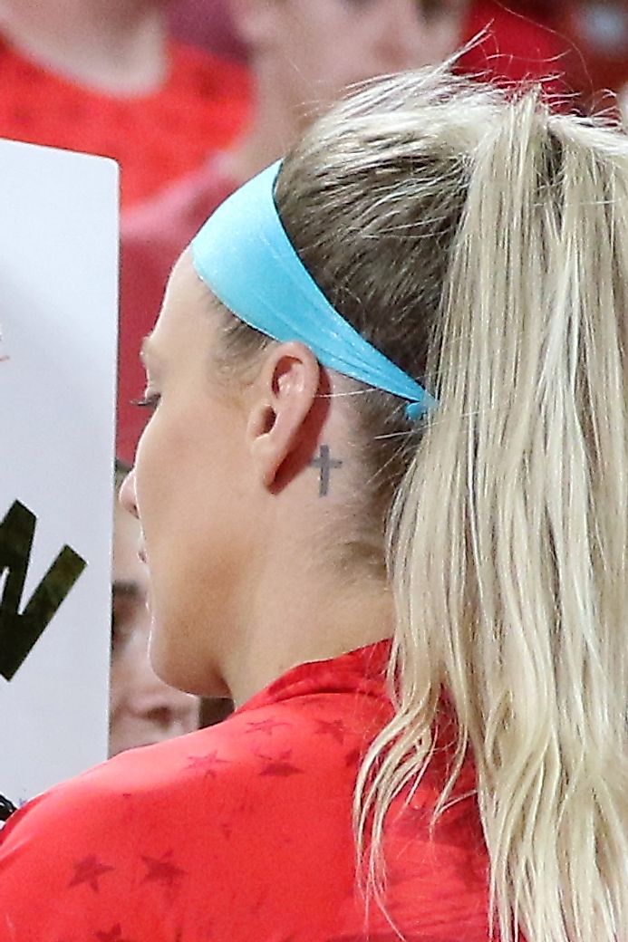 A cosmetic tattoo of a small cross, seen on Julie Ertz of the USA women's soccer team. Source: Wikimedia/Jamie Smed