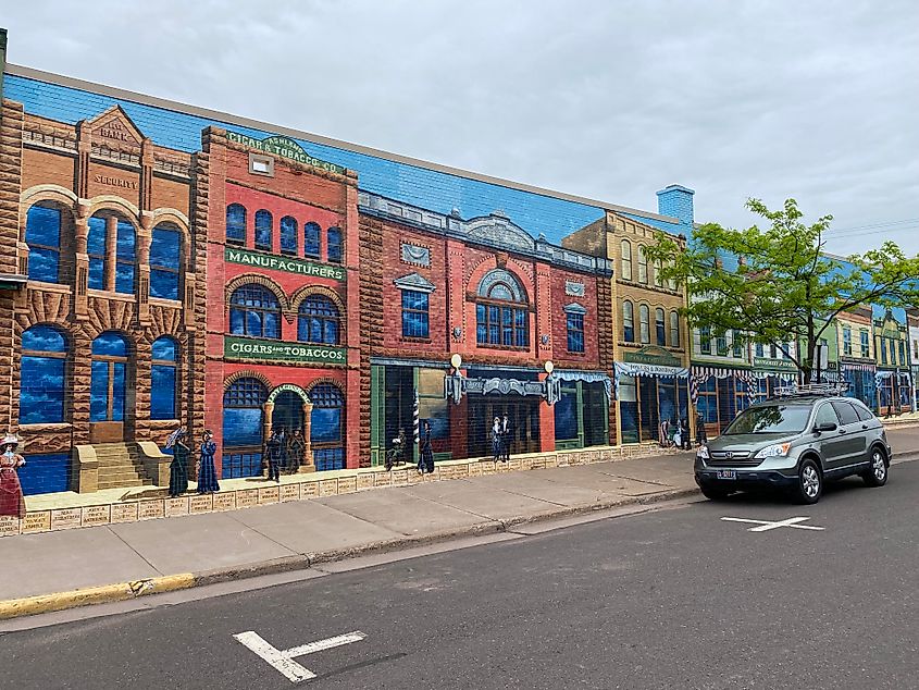 A colorful mural depicting old-fashioned store fronts covers the entire side of a building.