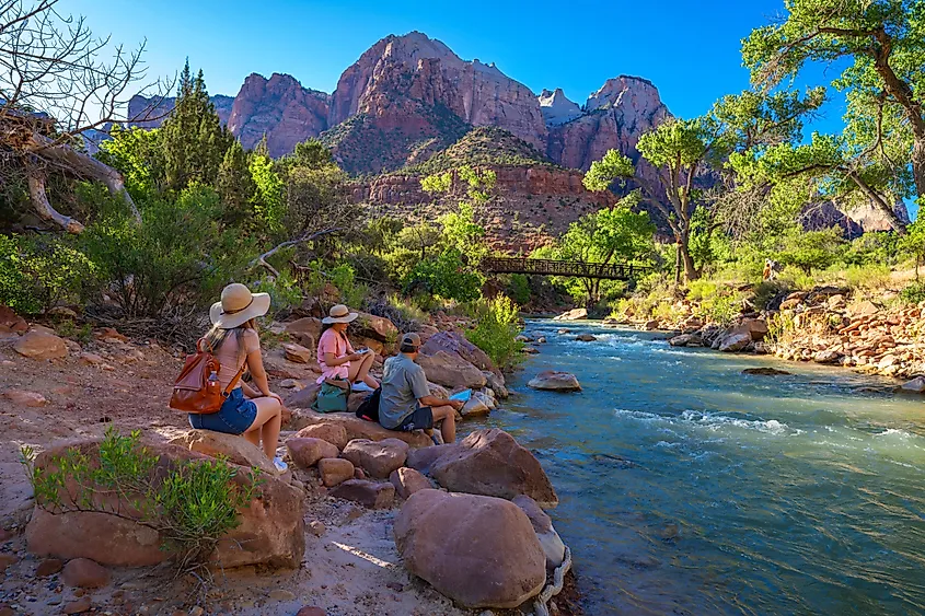 Visitors relax by a river in Zion National Park near Springdale, Utah.