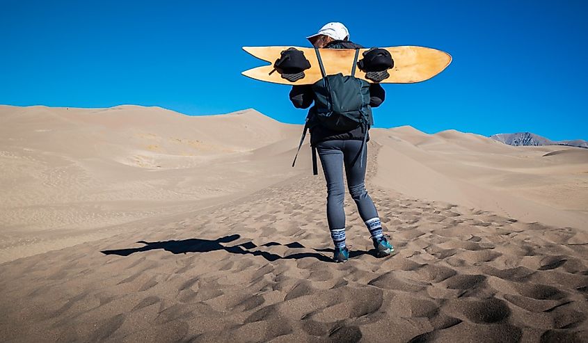 Adventurous female in the Great Sand Dunes National Park with a Sand Board