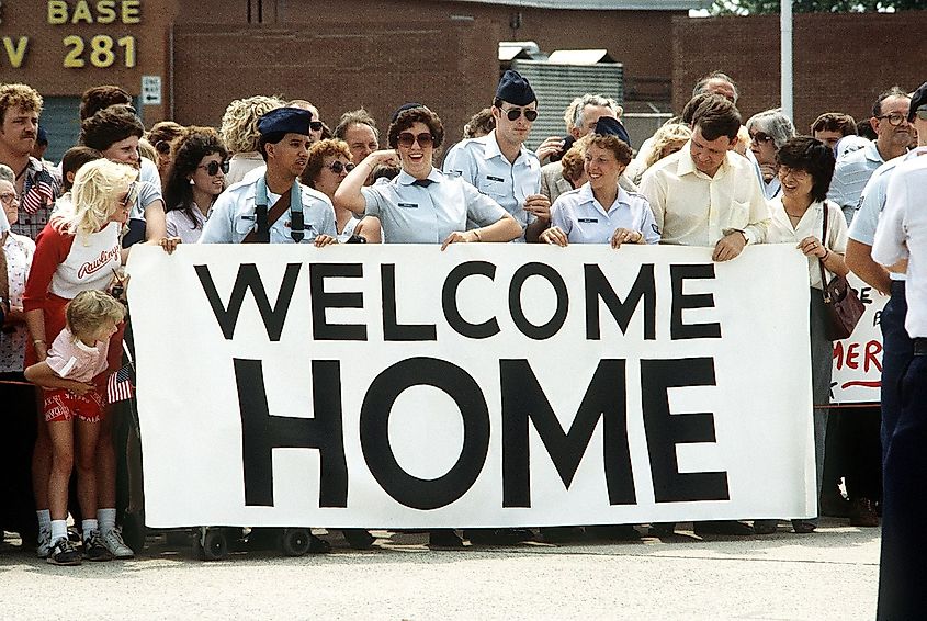 A crowd carrying a welcome home banner waits to greet former TWA hostages arriving back to the US