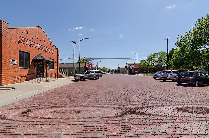 Downtown Gretna, Nebraska, featuring a brick-paved street with parked cars and the "City of Gretna" building prominently displayed.