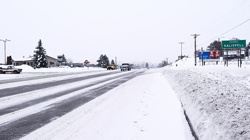 Vehicles driving past the Kalispell city limits sign on Highway 2 during a blizzard.