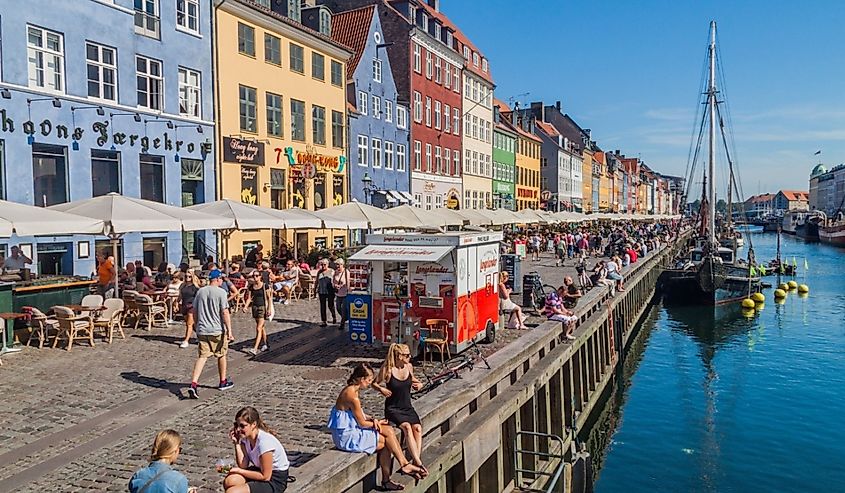 People enjoy sunny weather in Nyhavn district of Copenhagen, Denmark