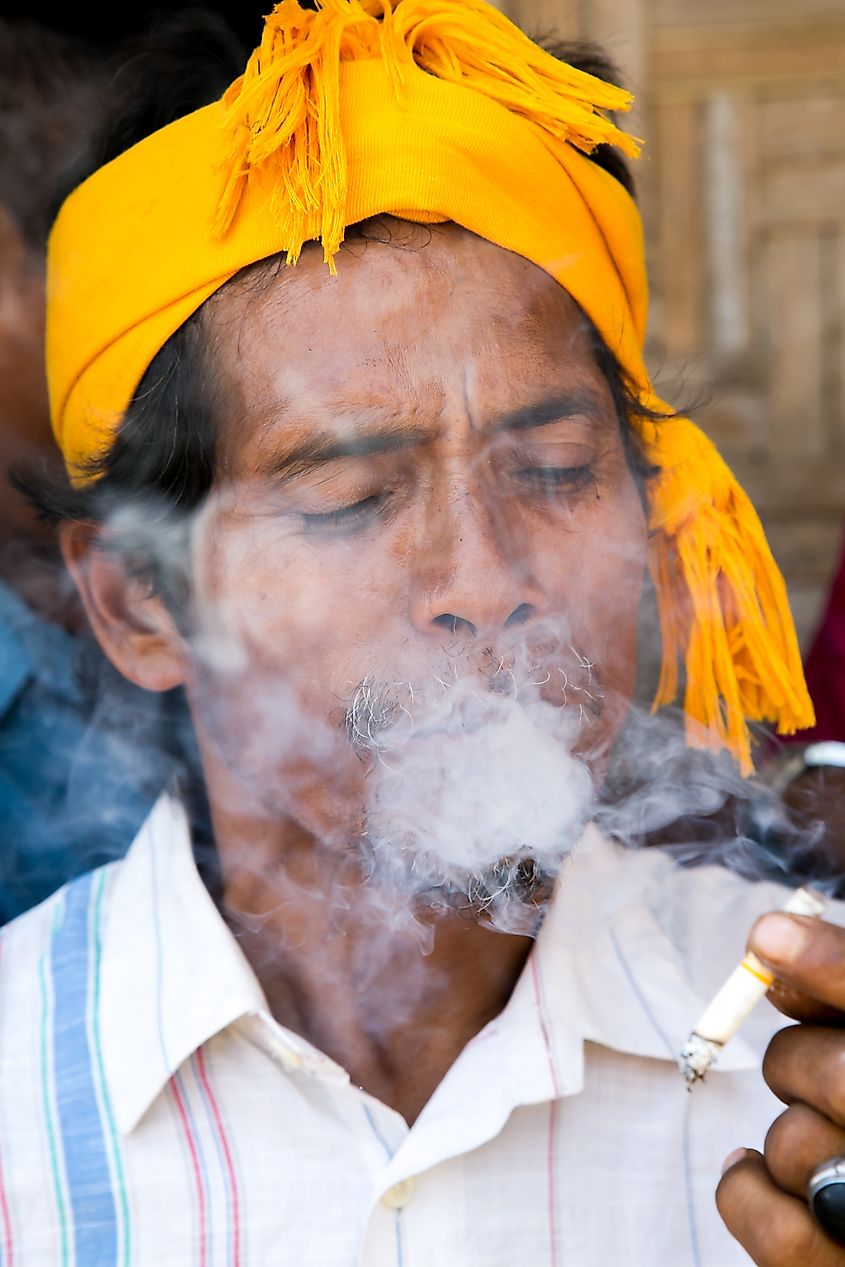 An Indonesian man in traditional dress smoking a cigarette. Editorial credit: Bob Pool / Shutterstock.com