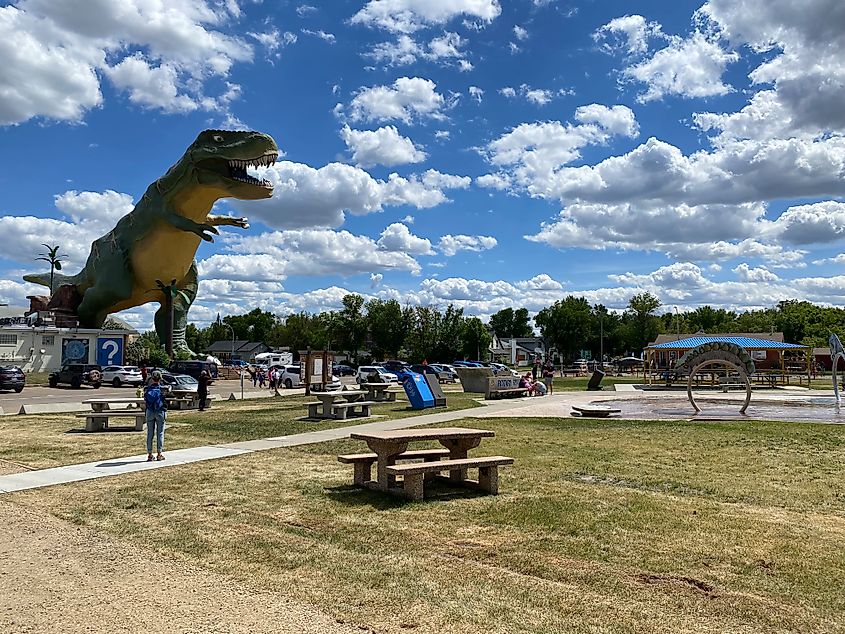 The 25-meter-tall, green and yellow T-Rex known as "Trya" looms large in front of a cloudy blue sky.  