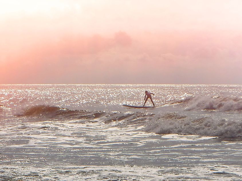 A young surfer riding a wave at sunrise on Folly Beach, South Carolina.