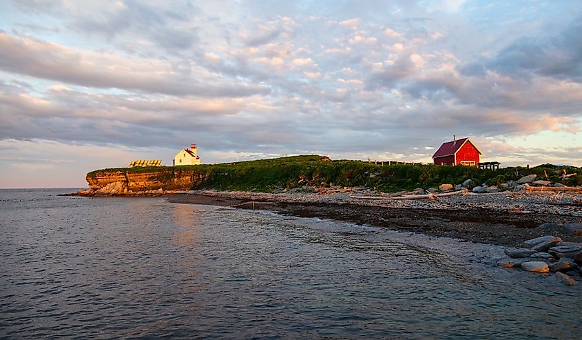 The small Île aux Perroquets (Parrots Island) in the Mingan Archipelago National Park Reserve with its lighthouse and a few historic wooden houses, Quebec, Canada.