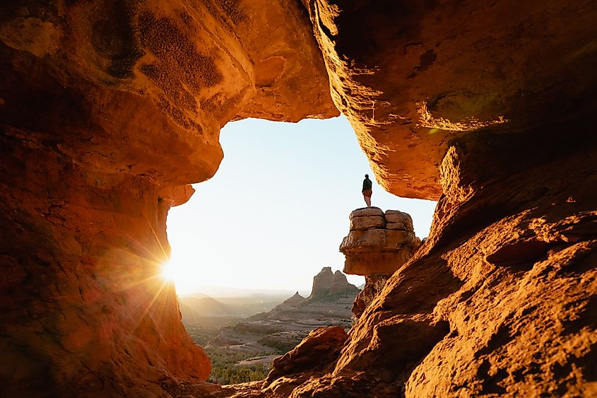 Woman standing at Merry-go-round Rock viewpoint in Sedona, Arizona, admiring the sunset landscape.