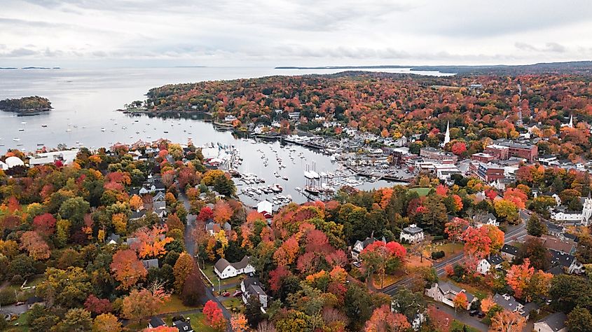 Drone view of Camden, Maine, showcasing vibrant fall colors as the autumn leaves blanket the town and surrounding hills.