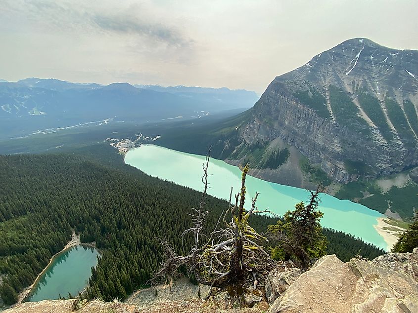 The milky blue mass of Lake Louise and small, reflective surface of Mirror Lake as seen from the mountain above. 