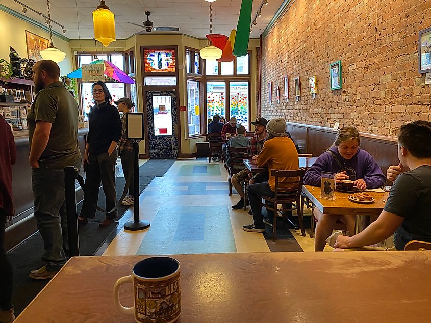 POV picture of a coffee mug from inside a full and colorful coffee shop