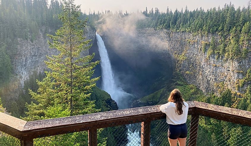 A young woman admiring the view of Helmcken Falls, an incredibly beautiful waterfall. Helmcken Falls is on the Murtle River within Wells Gray Provincial Park in British Columbia, Canada