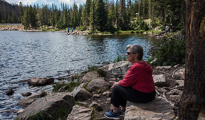 Woman in red shirt gazing over the tranquil waters of a high mountain lake.