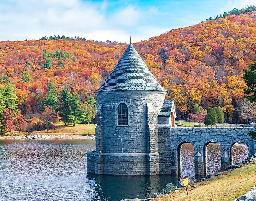Saville Dam with colorful trees covering hills in the background, Barkhamsted, Connecticut.