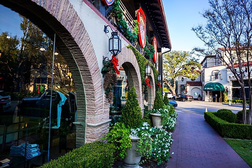 Beautifully decorated brick wall near a sidewalk in Highland Park Village, Texas, during the Christmas season.