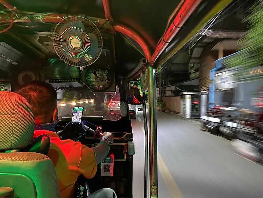 A POV pic of a passenger in the back of a tuk-tuk as it speeds through the streets at night. 