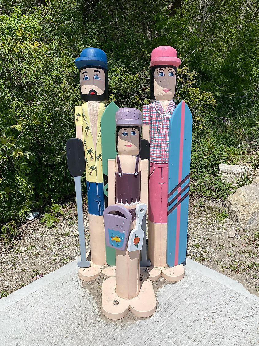 Three cartoonish wooden statues made to resemble a beach-going family.