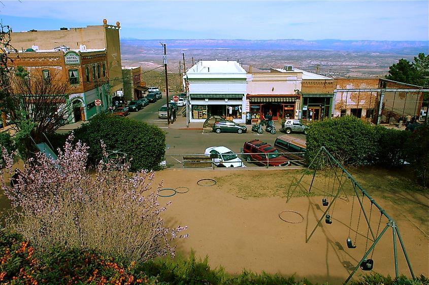 A view of downtown Jerome, Arizona, showcasing historic buildings, including the Hotel Connor, and a small park with swings in the foreground. 