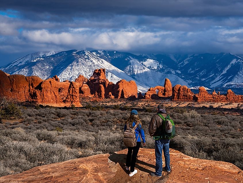 A couple enjoying a scenic mountain view during a hiking trip in the Windows Section of Arches National Park, Moab, Utah