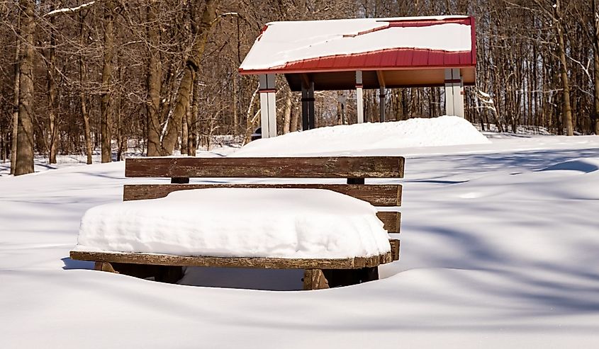 Snow stacked on a bench in winter at Schoenlaufen Park in Germantown, Wisconsin.