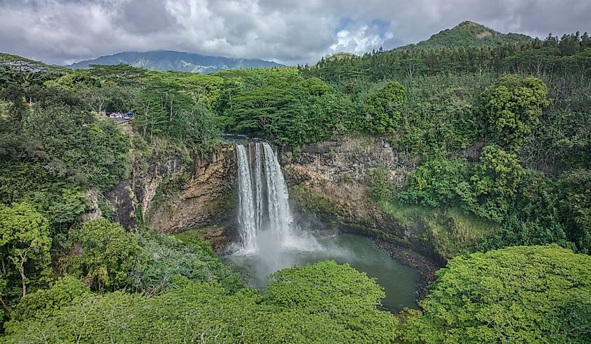 Aerial view over the Wailua Falls waterfall emerging from the tropical rainforest of Kauai Island in Hawaii.