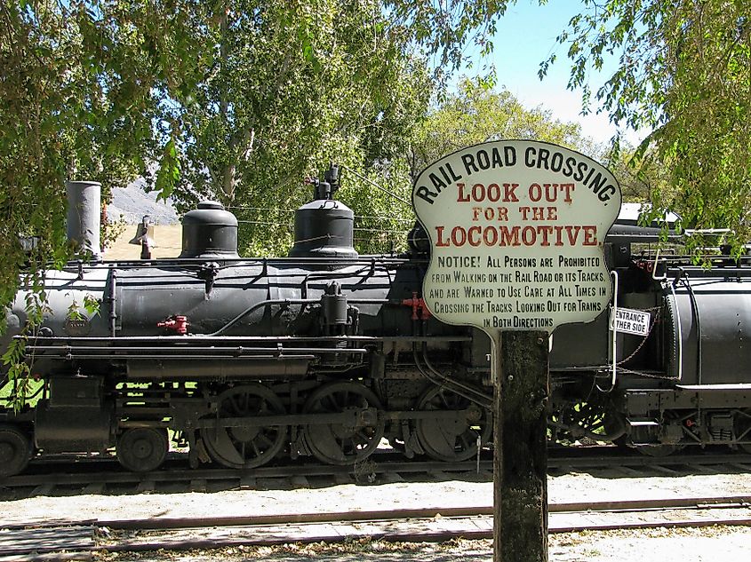 A vintage look out for the locomotive crossing sign warned travelers not to cross the tracks, with a 1909 narrow gauge steam engine in the background.