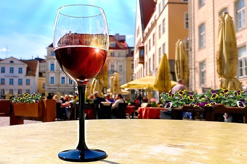 Glass of wine, street restaurant glass of red wine on table top people relaxing on city Tallinn old town tourist in summer city travel to Estonia