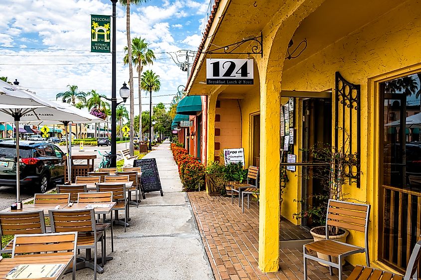 Welcome to the historic old town of Venice, Florida, featuring a sidewalk restaurant with outdoor seating at 124, with empty chairs and tables on display.