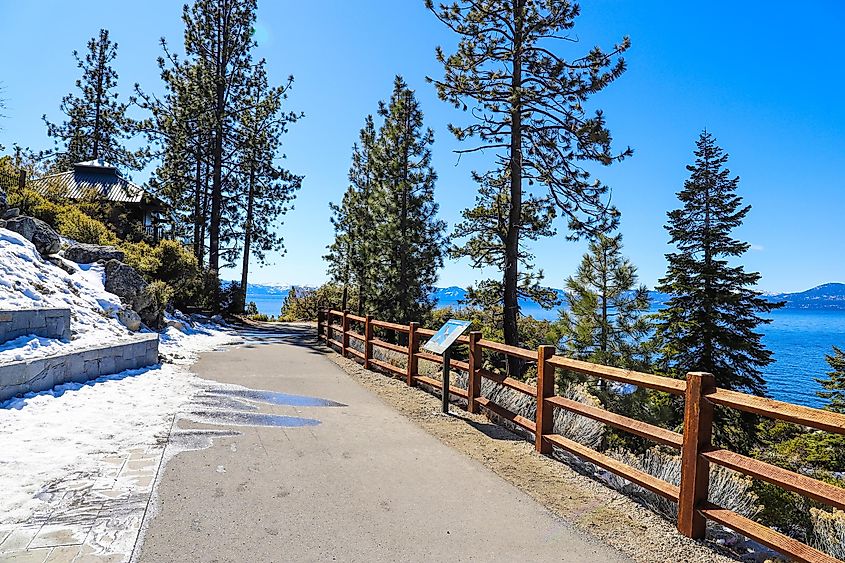 Lake Tahoe, Nevada: A long, smooth concrete walking path with a wooden fence alongside a vast, deep blue lake.